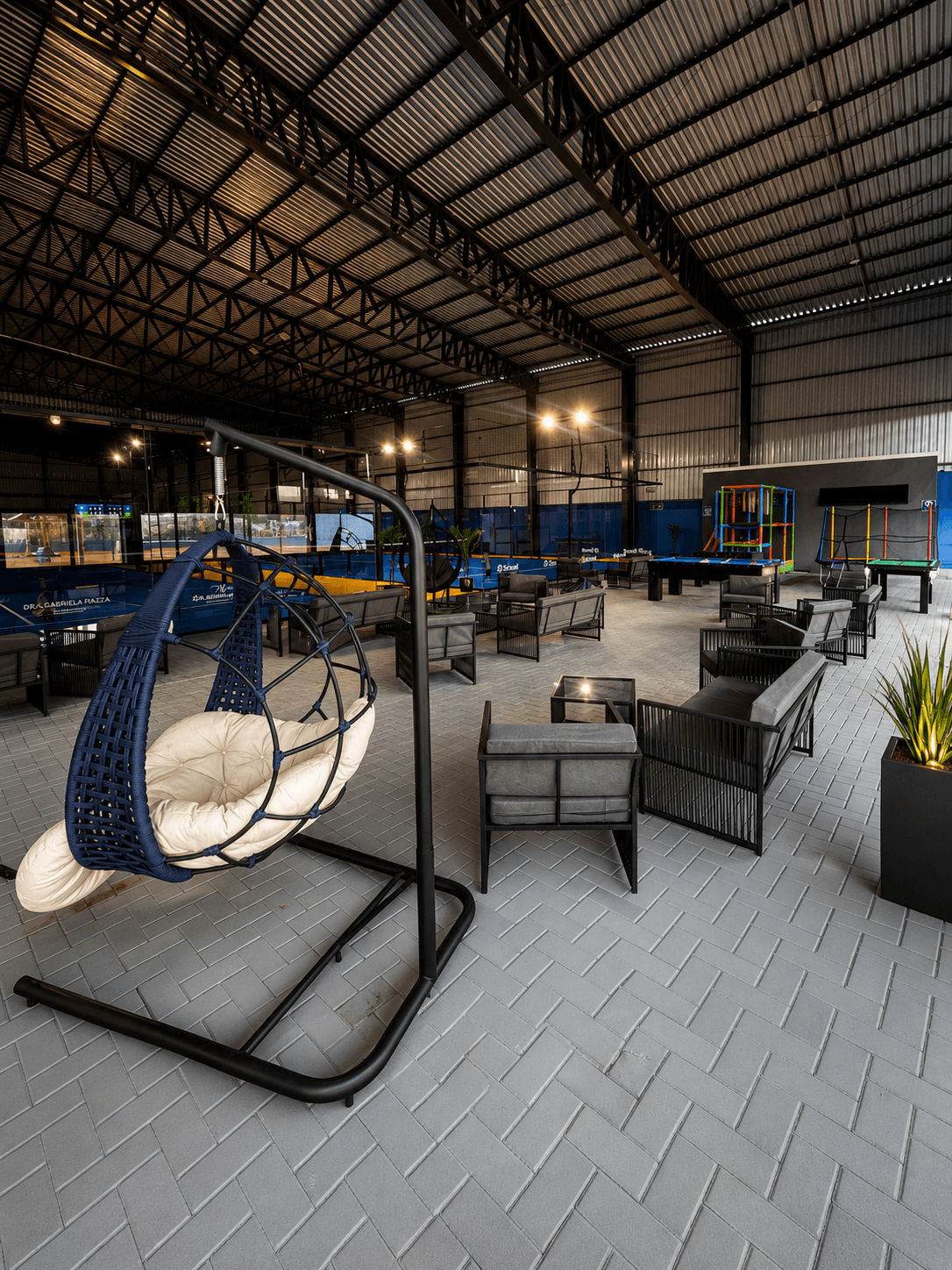 Área de convivência da Arena Bitz com lounge e quadras ao fundo