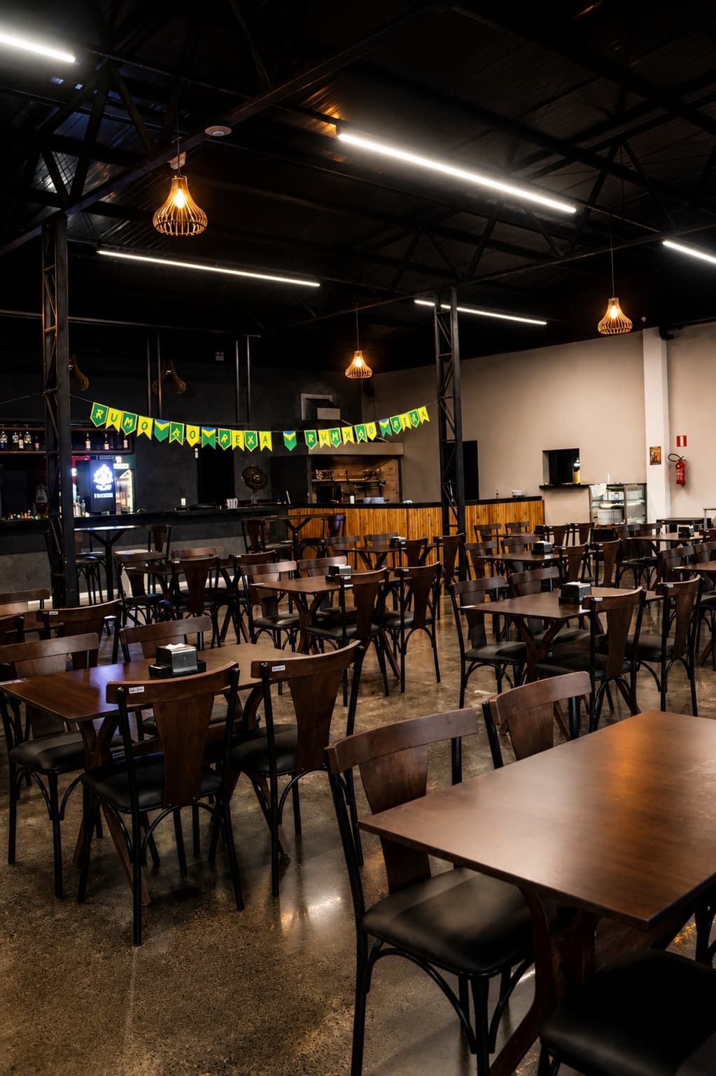 Salão do restaurante Maestro Sport Bar com mesas e bar ao fundo