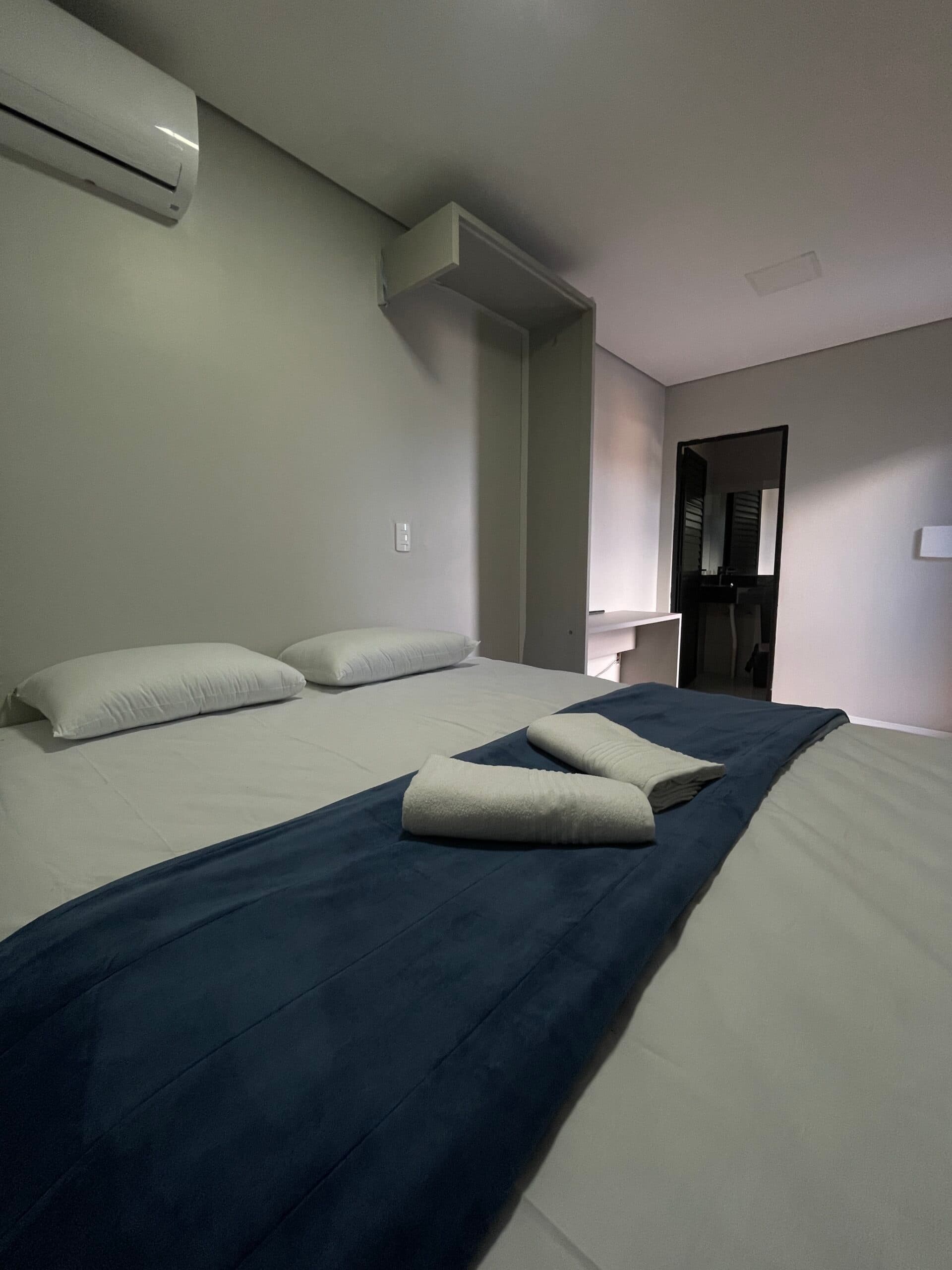 Quarto Standard do Hotel Arena Bitz com piso amadeirado e enxoval branco